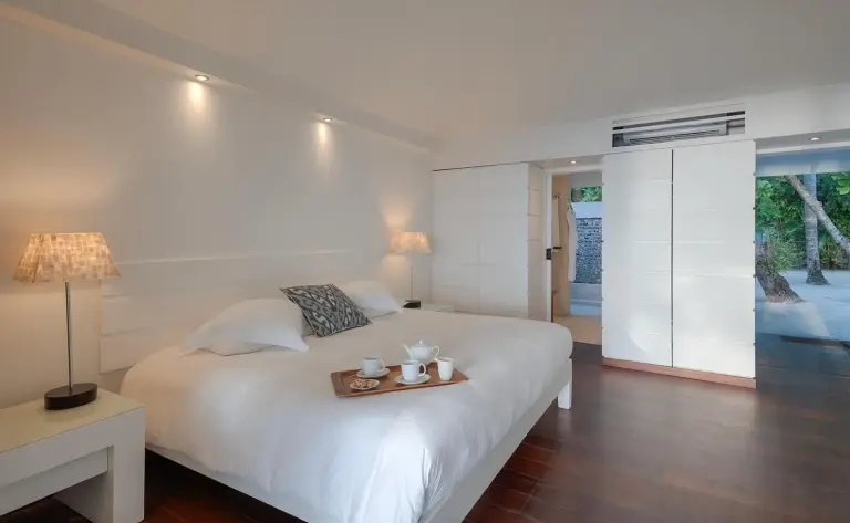 Elegant bedroom in a suite at Diamonds Thudufushi Maldives Resort & Spa with breakfast served.