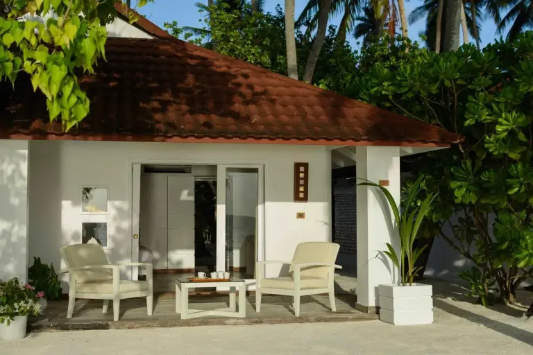 Exterior view of a villa at Diamonds Thudufushi Maldives Resort & Spa surrounded by lush greenery.