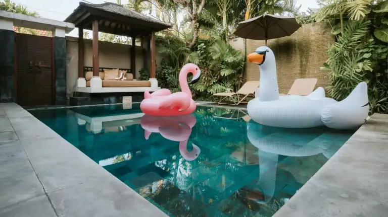 Private pool at DISINI Luxury Spa Villas-CHSE Certified in Seminyak with flamingo and swan floats in a tropical courtyard