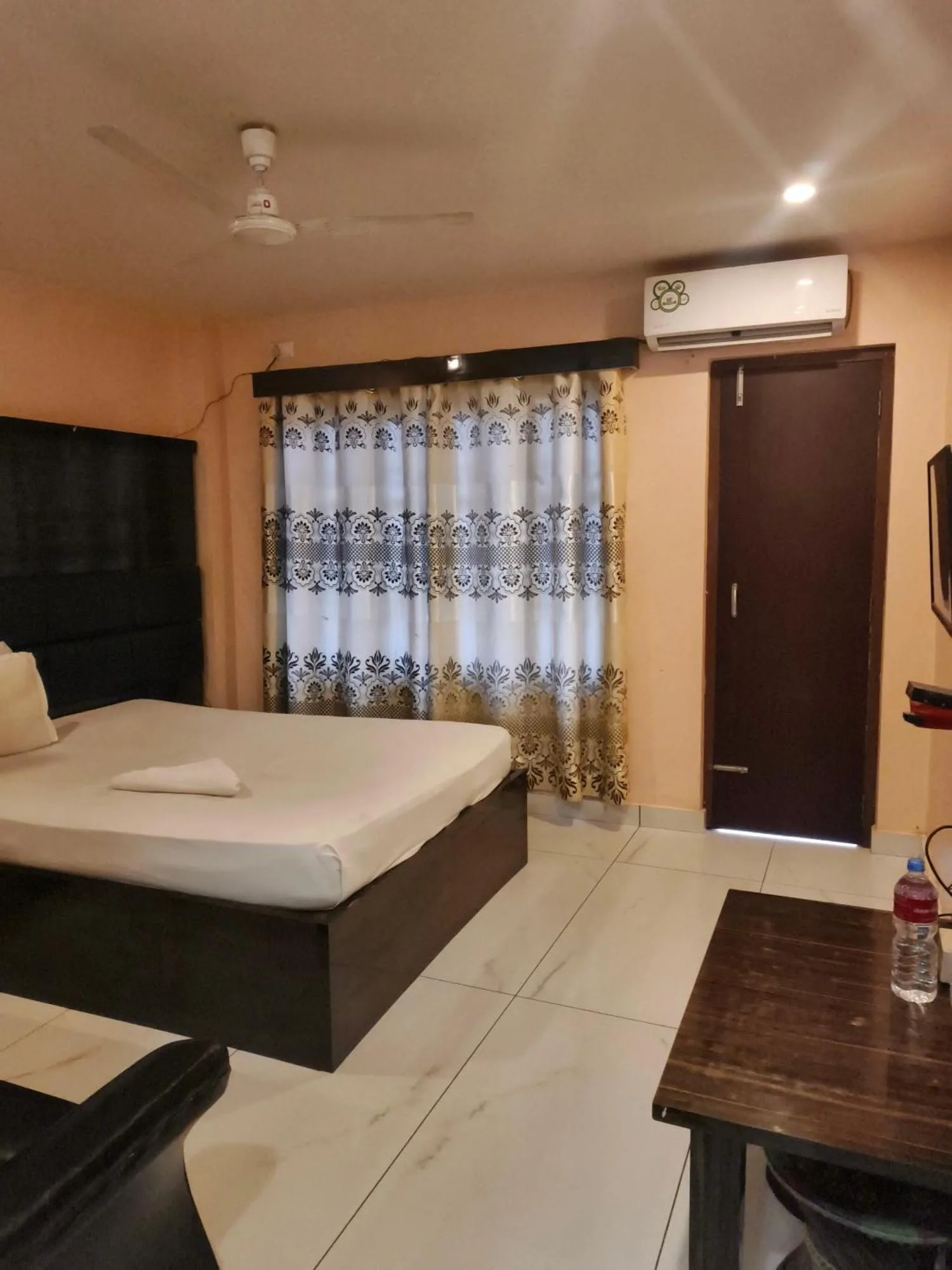 Habitación doble de Domukha Pali Ghar en Birtamod con una cama, ventana con cortinas y aire acondicionado.