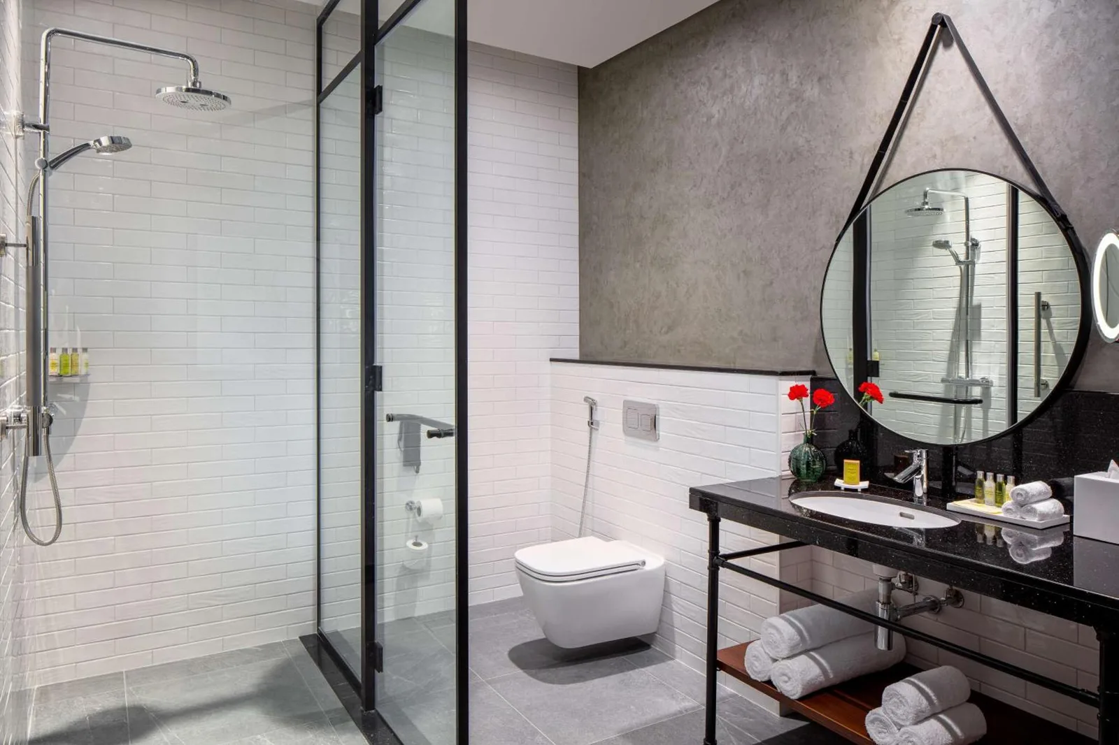 Modern bathroom at DoubleTree by Hilton Dubai M Square Hotel & Residences in Dubai with walk-in shower, vanity, and toilet