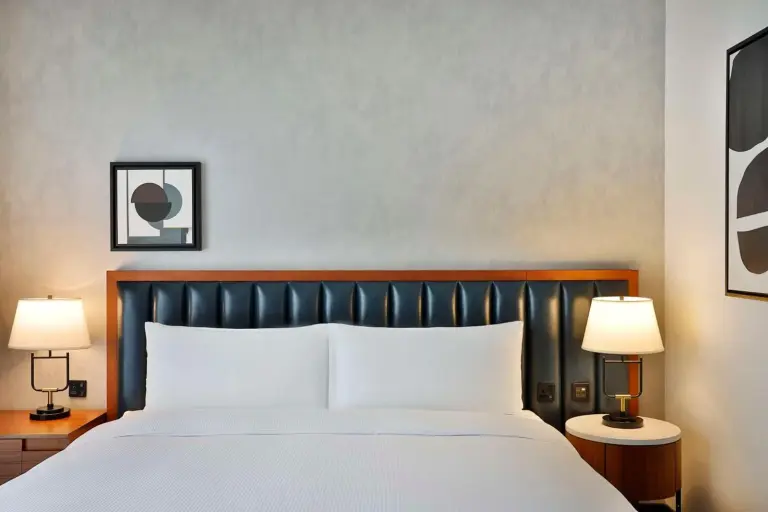 King bed in a guest room at DoubleTree by Hilton Dubai M Square Hotel & Residences in Dubai with bedside lamps and framed art
