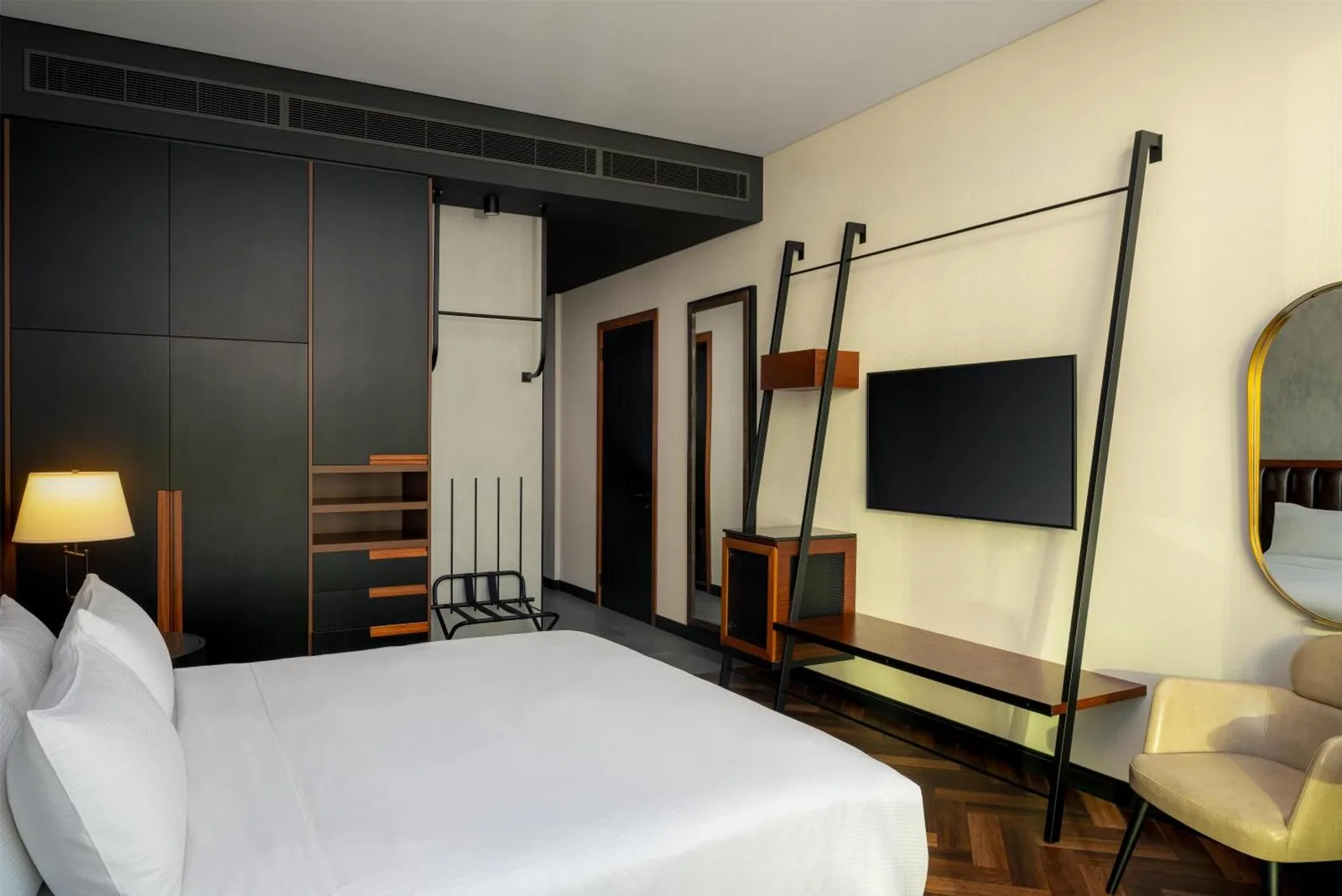 Contemporary guest room at DoubleTree by Hilton Dubai M Square Hotel & Residences in Dubai with wall-mounted TV and wardrobe