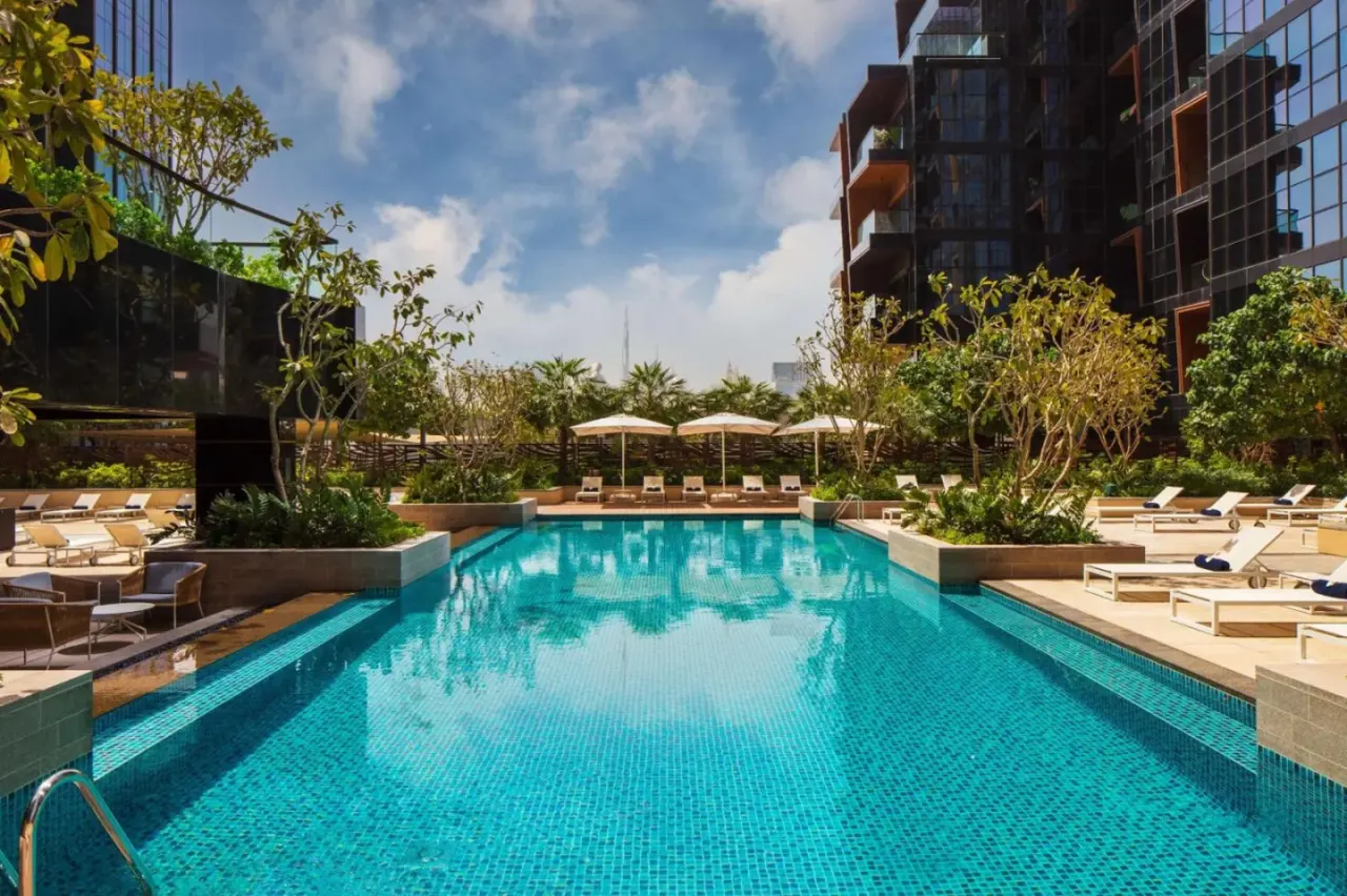 Outdoor pool area at DoubleTree by Hilton Dubai M Square Hotel & Residences in Dubai with sun loungers and palm landscaping