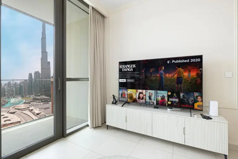 Living room with modern TV setup and Burj Khalifa view in hotel, Downtown Dubai.
