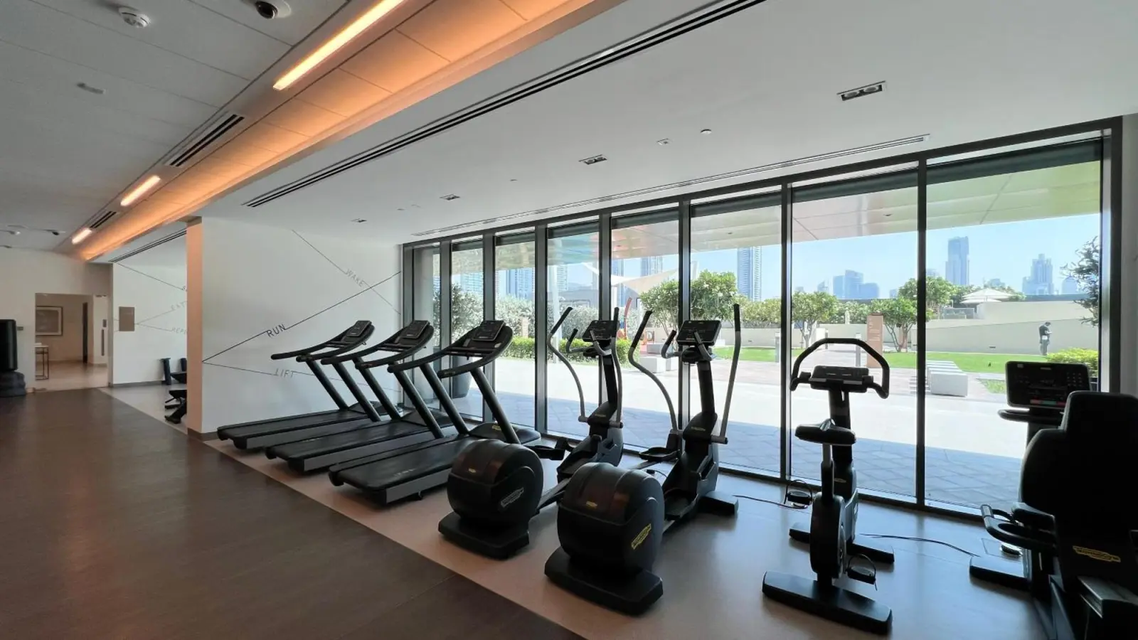 Modern hotel gym with fitness equipment and city view, Downtown Dubai.