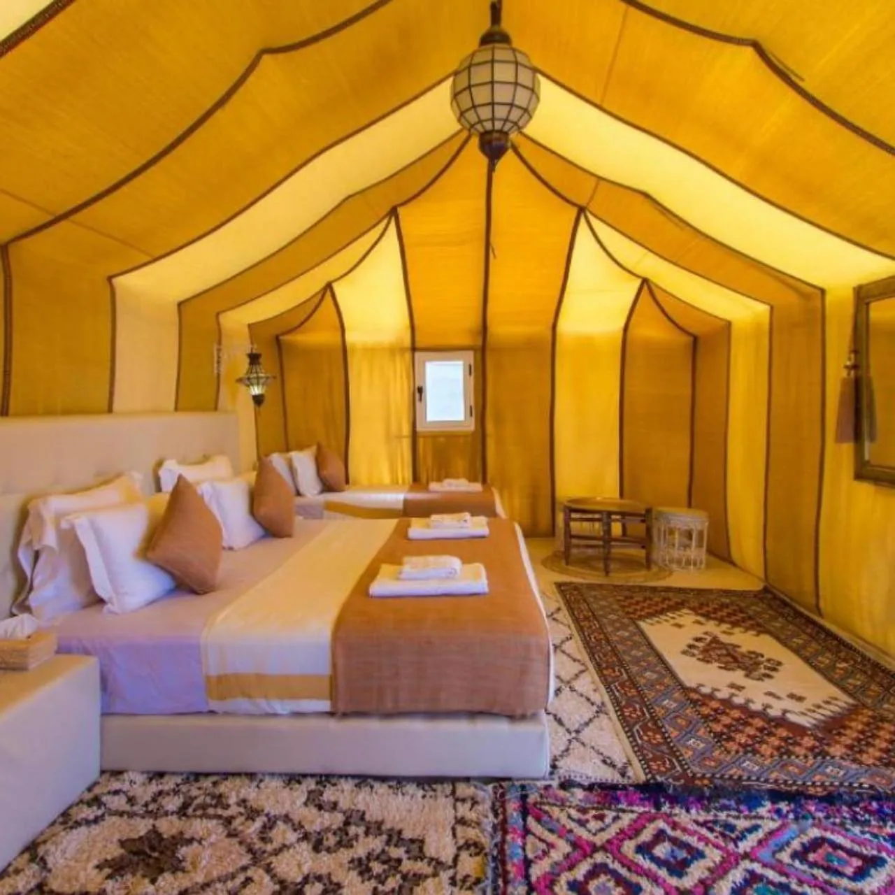 Dream Desert Camp in Merzouga luxury tent bedroom with twin beds and colorful rugs