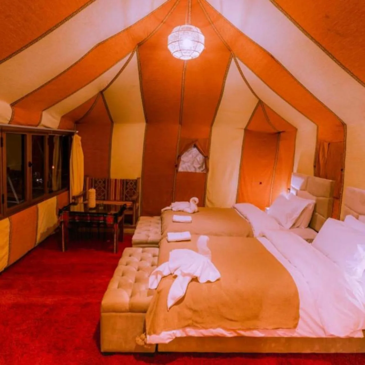 Dream Desert Camp in Merzouga deluxe twin tent room with red carpet and bedside table