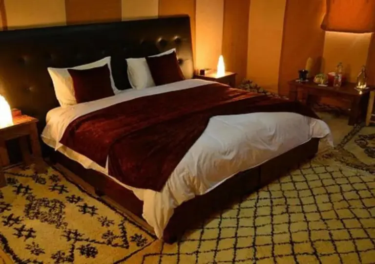 Luxury bedroom at Dune Majesty Luxury Camp Merzouga with large bed and warm lighting