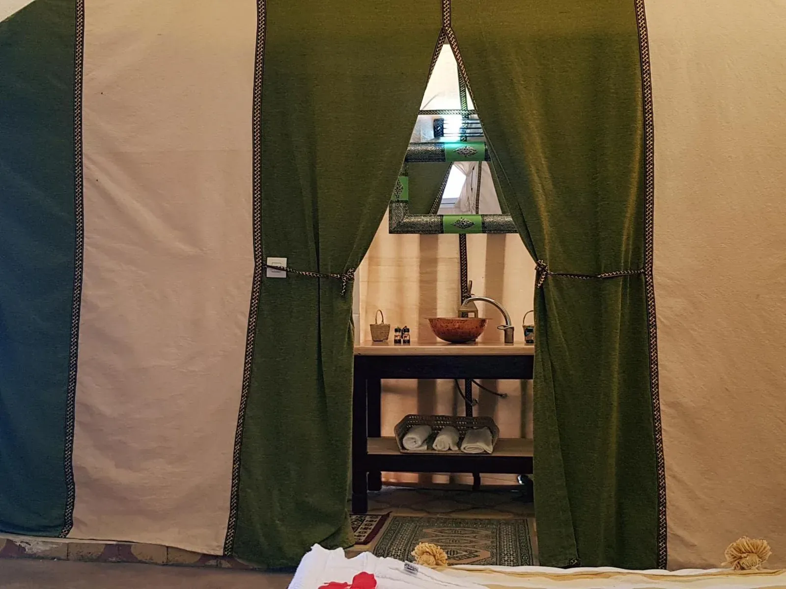 Inside bathroom entrance at Dune Merzouga Camp in Merzouga with green curtains and sink vanity