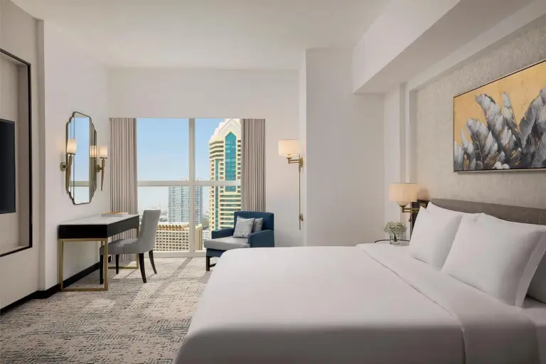 Dormitorio de Dusit Thani Dubai con escritorio, asiento junto a la ventana y skyline de la ciudad