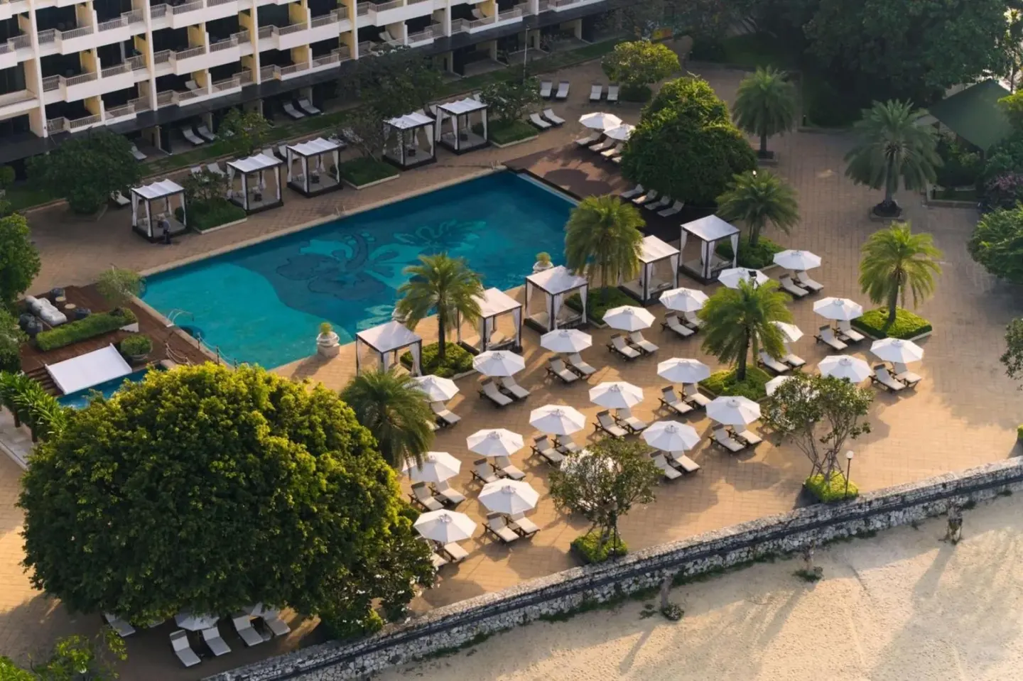 Zone de piscine du Dusit Thani Pattaya avec chaises longues et parasols