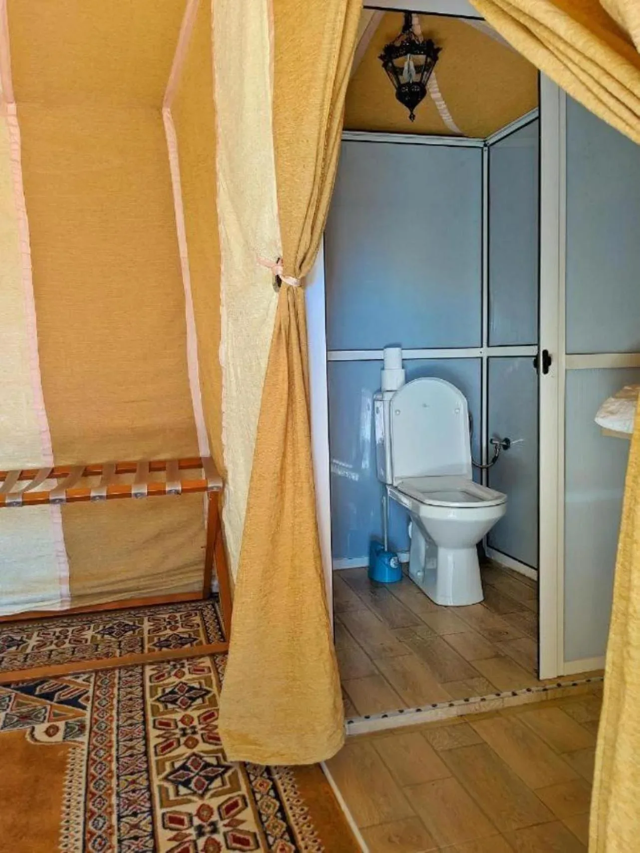 Salle de bains privée à l’intérieur d’une tente à Eclipse Luxury Camp à Merzouga avec toilettes et espace fermé par un écran.