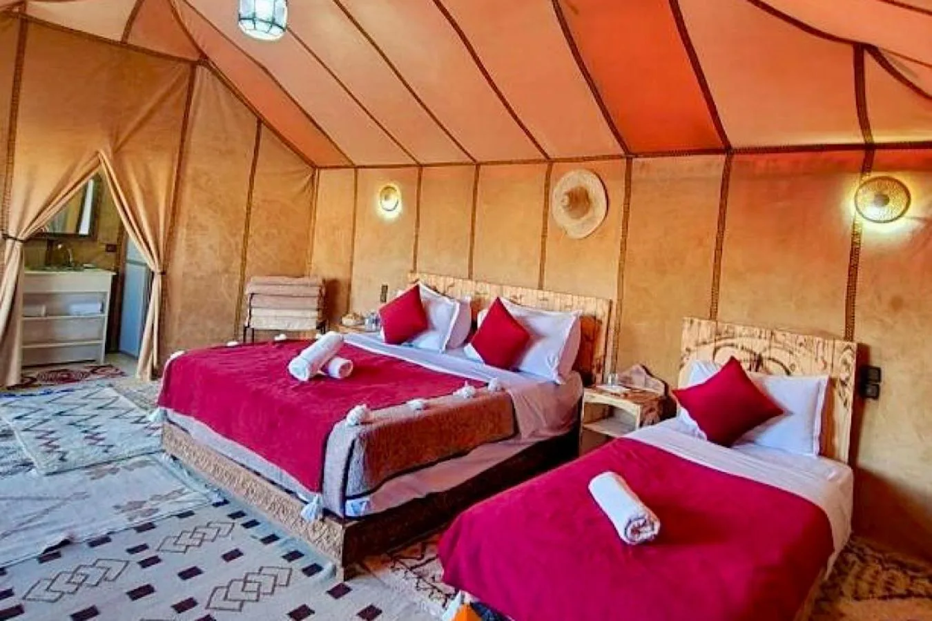Intérieur d’une tente double pour les clients à Eclipse Luxury Camp à Merzouga avec literie rouge et décoration inspirée du désert.