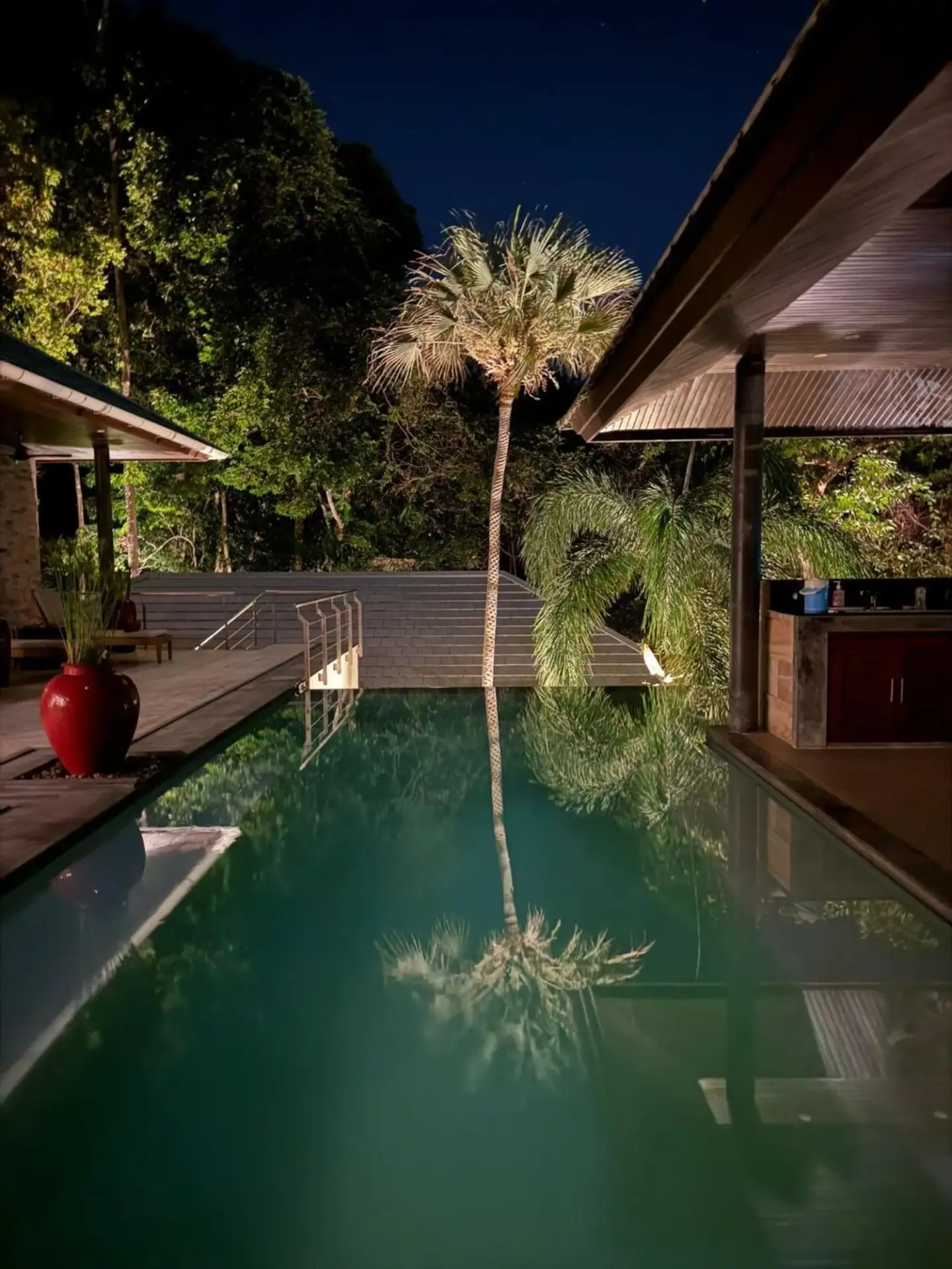 El Cid Villa pool reflecting palm trees at night in Koh Samui