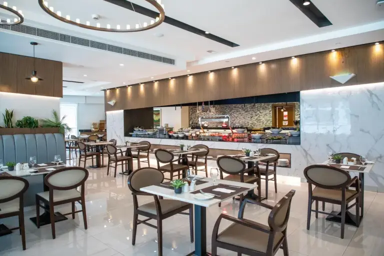 Espace restauration à Elite Byblos Hotel Dubai avec sièges modernes et touches vertes