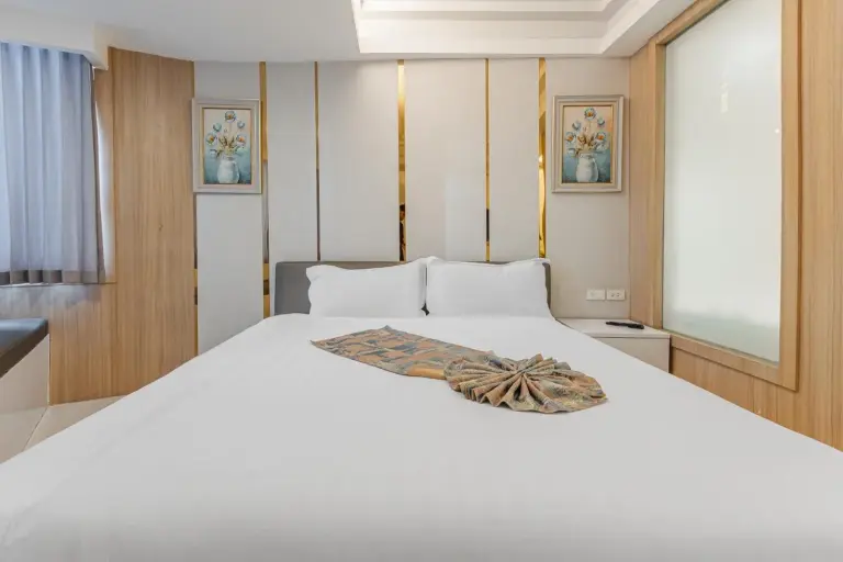 Front view of a king bed in a guest room at Elong Hotel Pattaya Jomtien Beach with decorative artwork