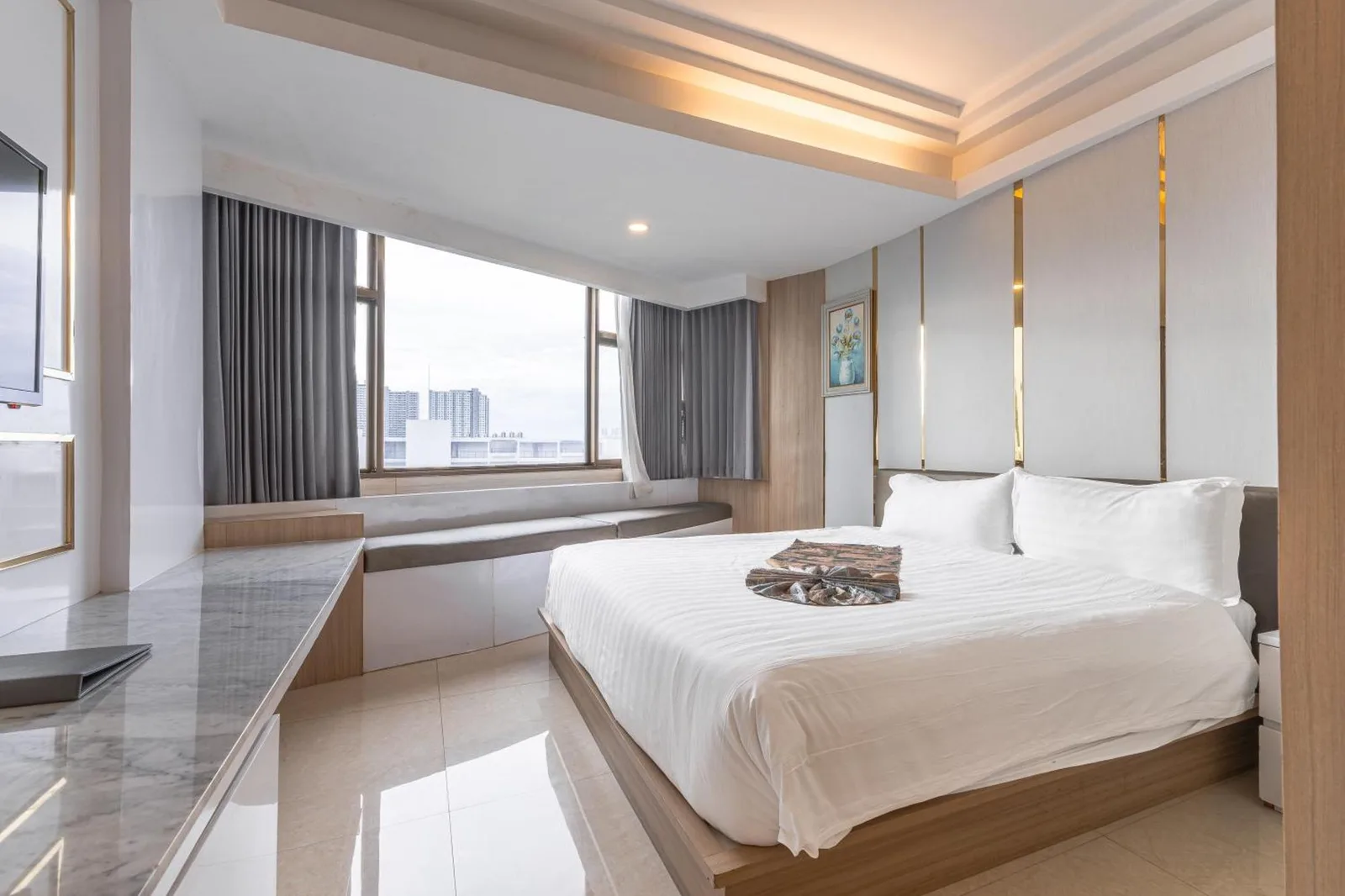 Bright deluxe guest room at Elong Hotel Pattaya Jomtien Beach in Pattaya with king bed and window seating
