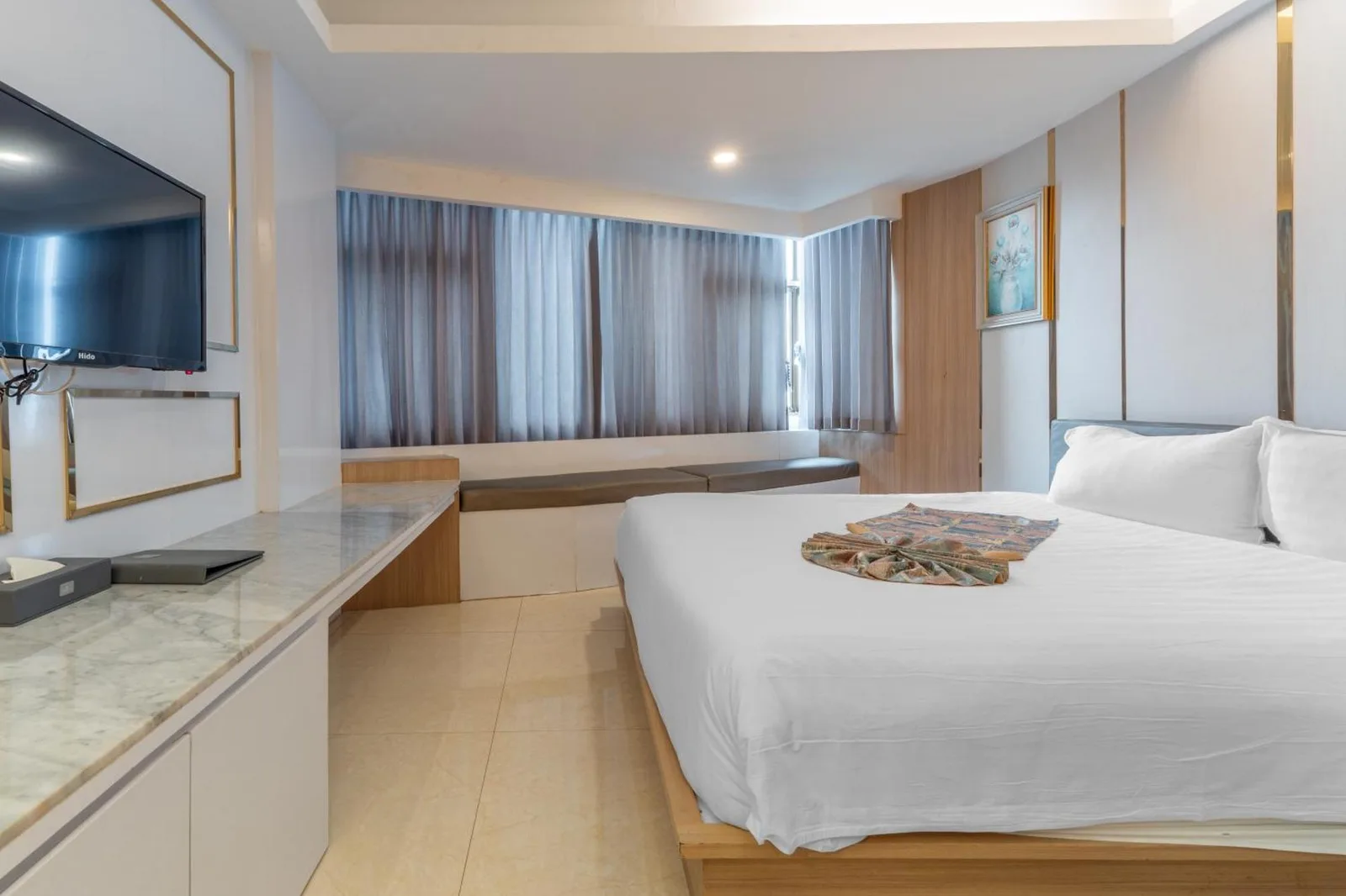 Spacious guest room at Elong Hotel Pattaya Jomtien Beach with king bed, curtains, and bedside table