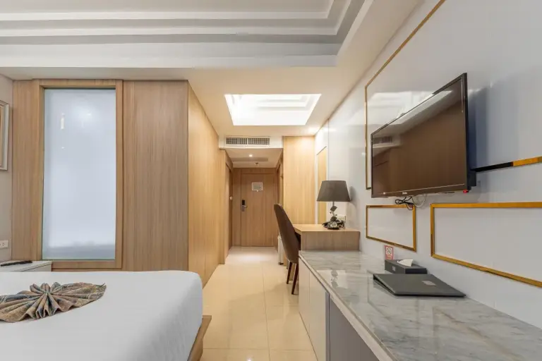 Long view of a guest room interior at Elong Hotel Pattaya Jomtien Beach with desk and TV wall