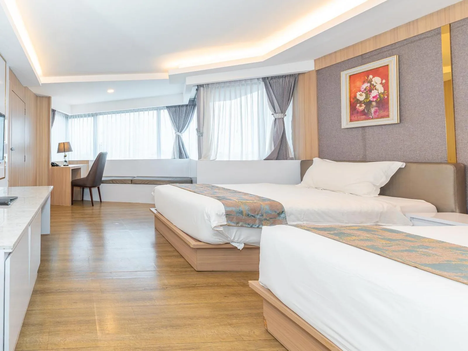 Twin guest room at Elong Hotel Pattaya Jomtien Beach with two beds, wooden flooring, and large windows