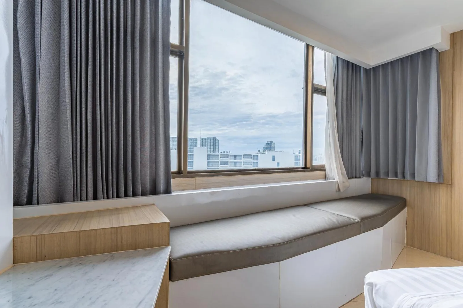 Window seating area in a guest room at Elong Hotel Pattaya Jomtien Beach overlooking Pattaya city views