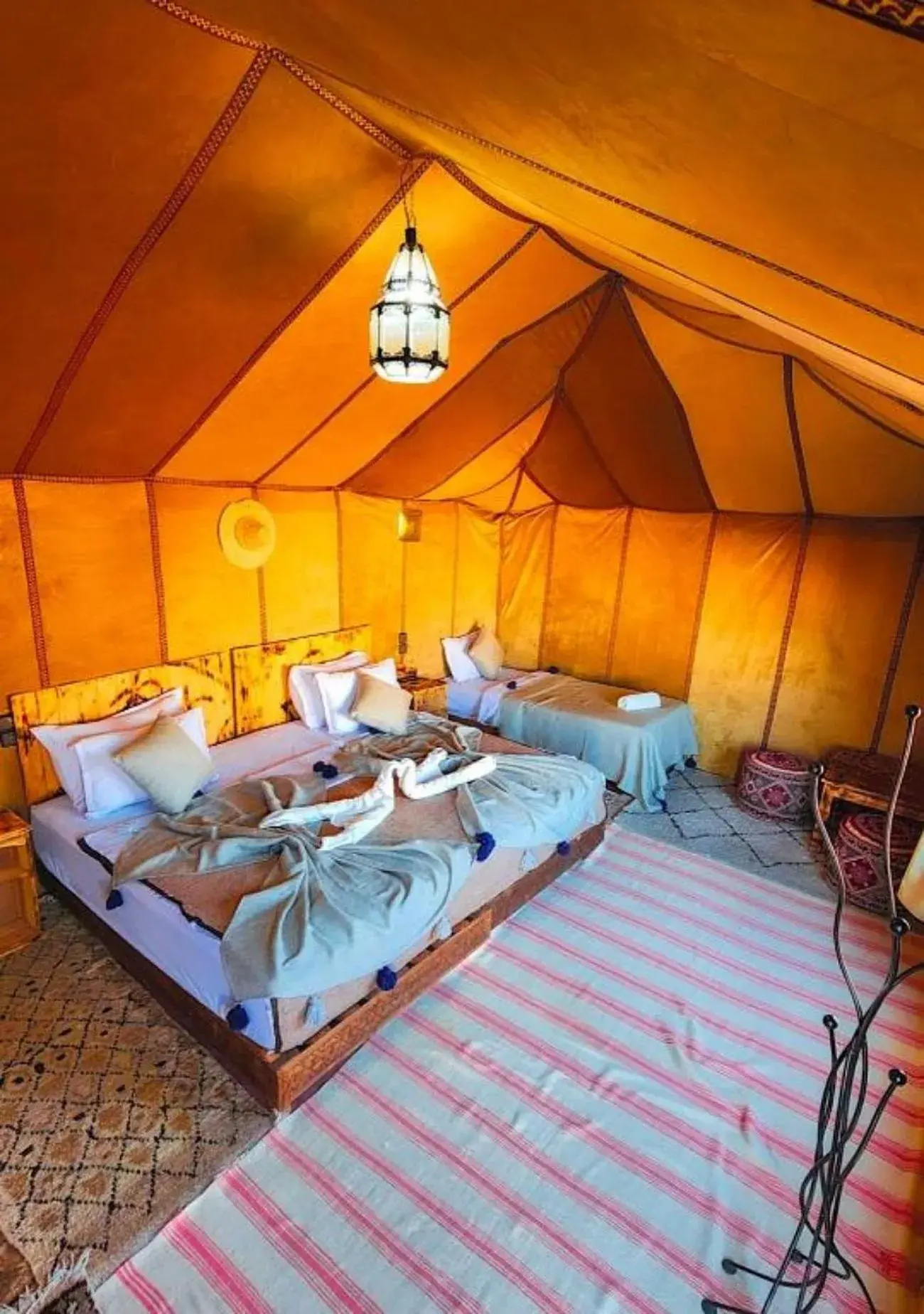 Intérieur des toilettes privées à Endless Sahara Camp à Merzouga avec des toilettes, un tapis et une lampe suspendue.