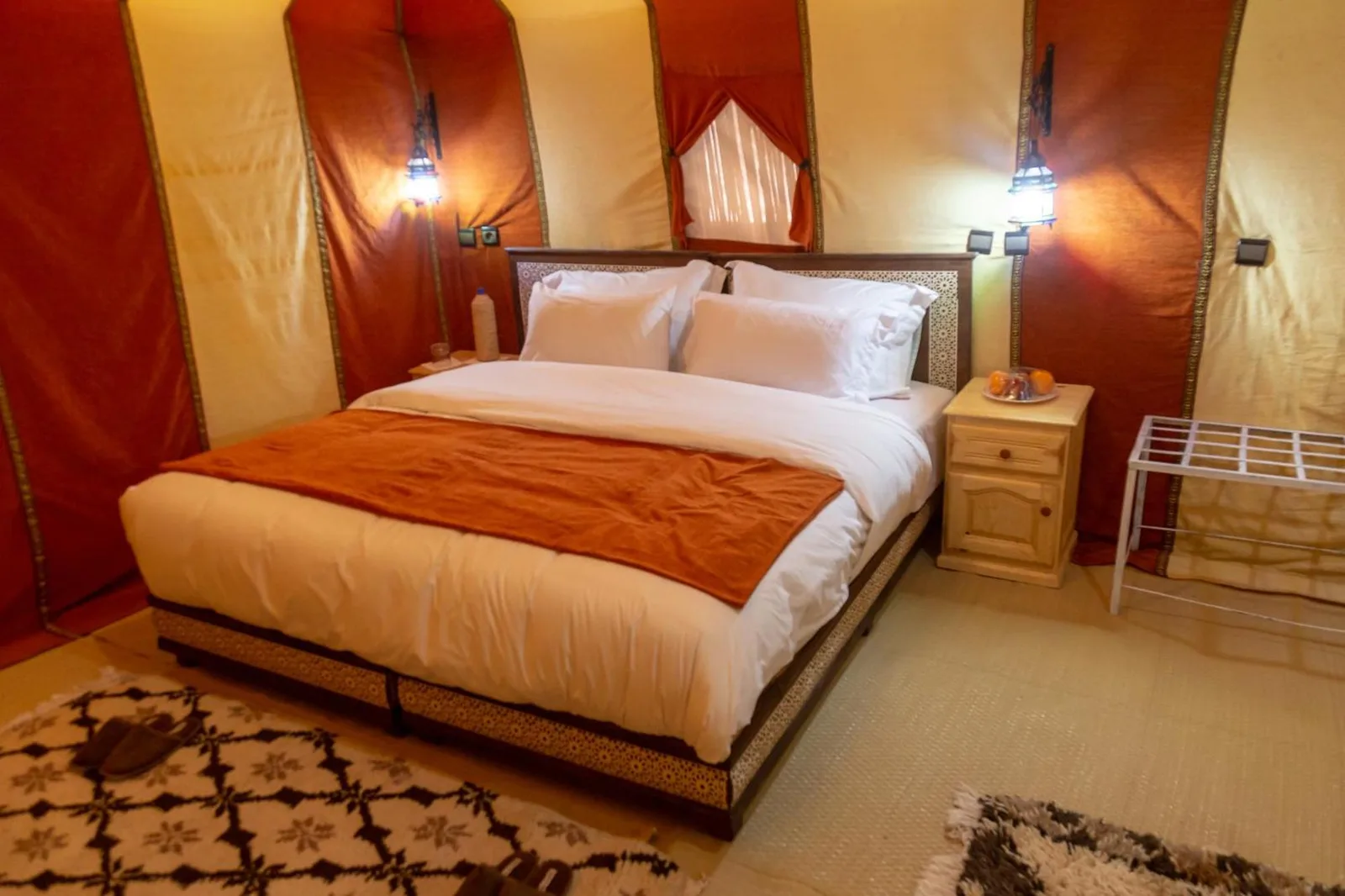 Elegant tent bedroom at Erg Chebbi Camp & Activities in Merzouga with red and cream Moroccan decor