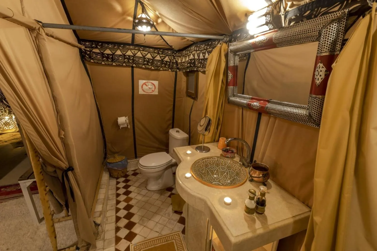 Bathroom at Erg Chebbi Desert Camp And Activities in Merzouga with sink, toilet, mirror, and tented walls.