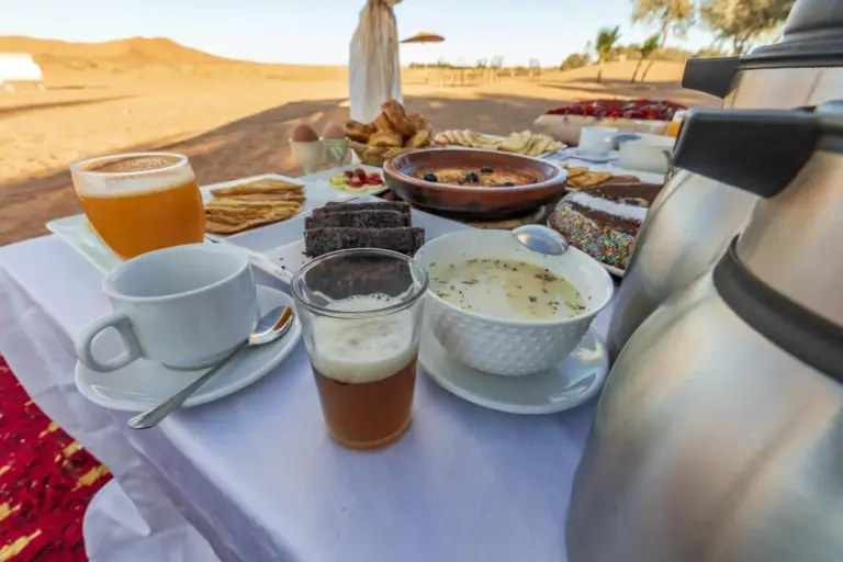 Breakfast spread at Erg Chebbi Desert Camp And Activities in Merzouga served outdoors near the desert dunes.