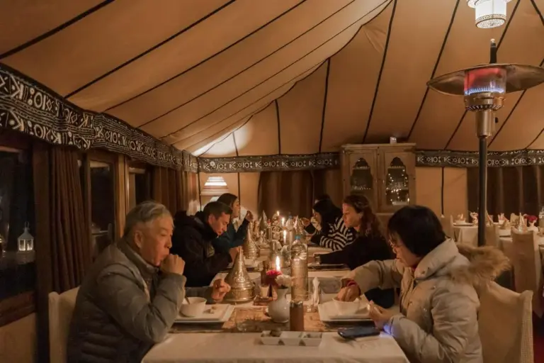 Guests dining inside Erg Chebbi Desert Camp And Activities in Merzouga under a large desert tent.
