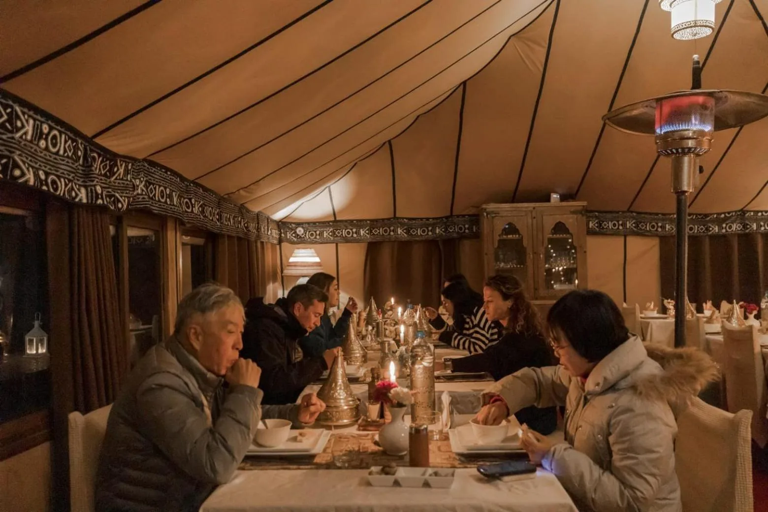 Guests dining inside Erg Chebbi Desert Camp And Activities in Merzouga under a large desert tent.