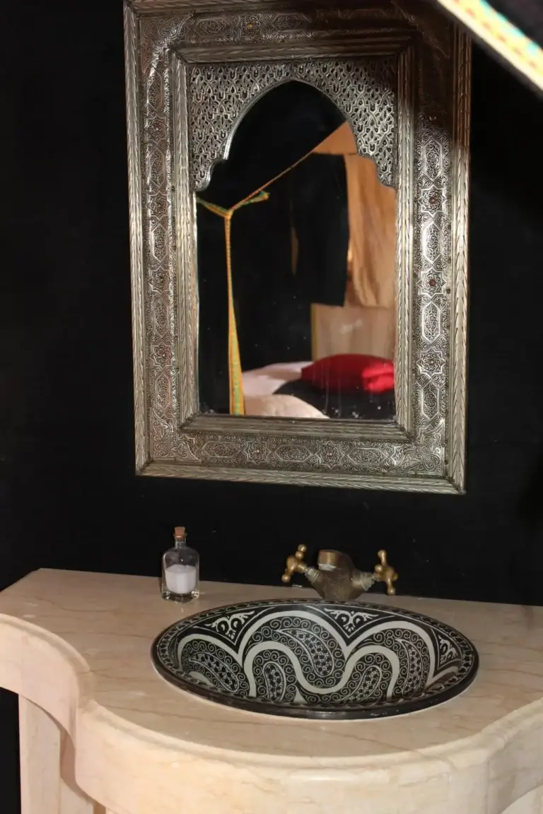 Decorative bathroom sink and mirror inside Erg Chebbi Luxury Camp in Merzouga