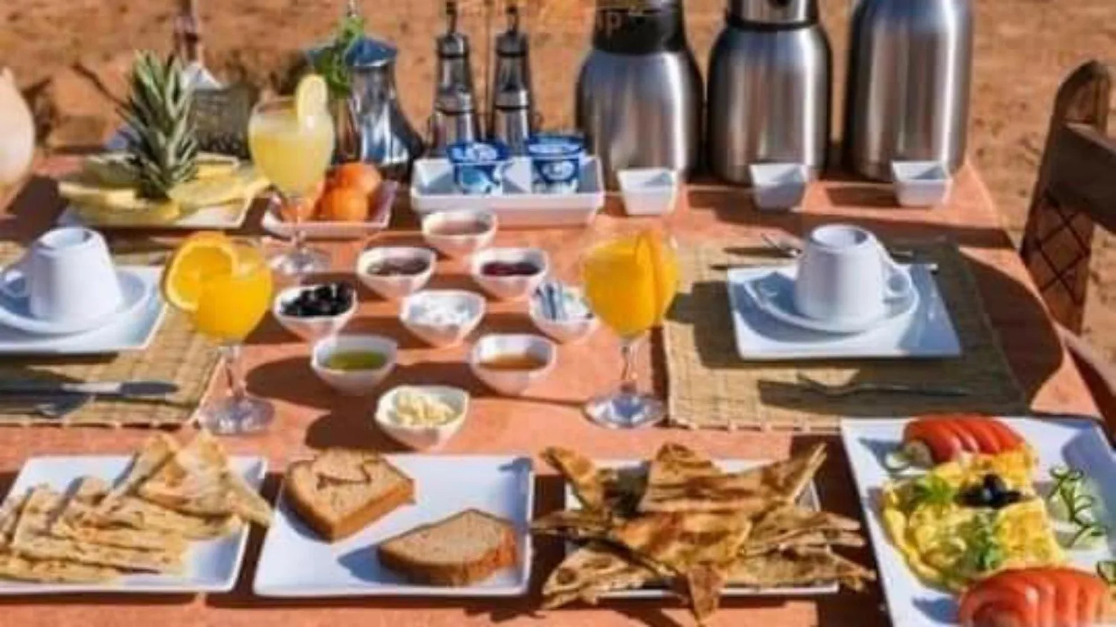 Breakfast spread at Erg Chebbi Luxury Camp in Merzouga with fresh fruit, juices, and pastries