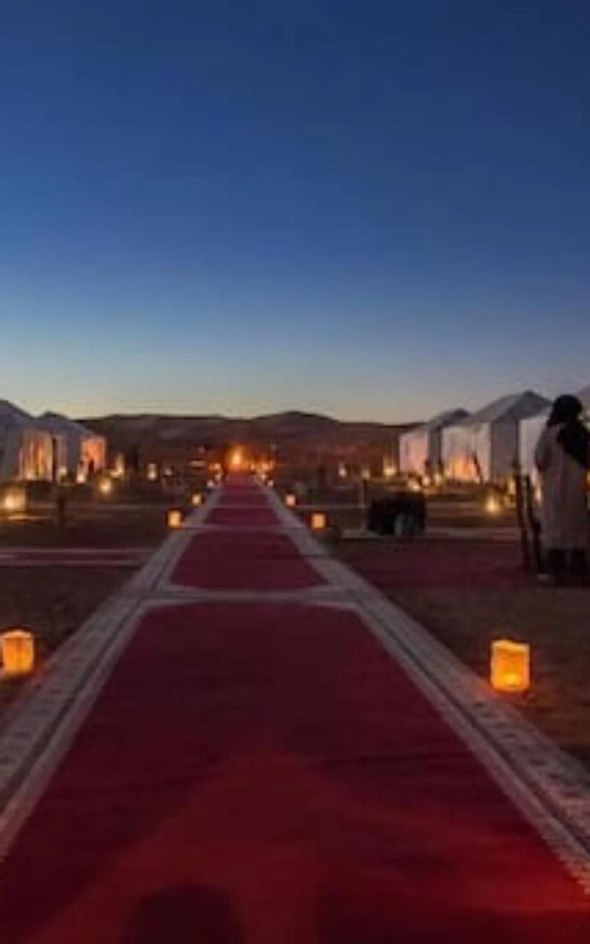 Red carpet walkway lined with lanterns at Erg Chebbi Luxury Camp in Merzouga