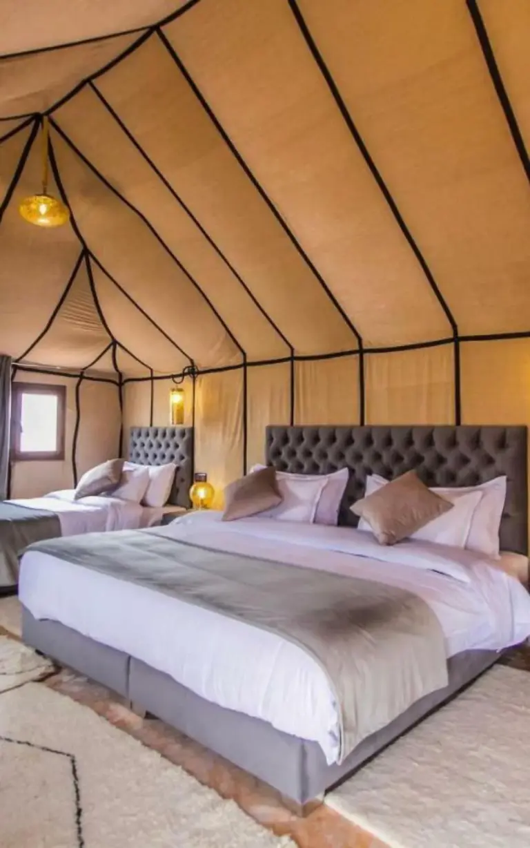 Luxury tent interior at Erg Chebbi Luxury Camp in Merzouga with twin beds and warm desert decor