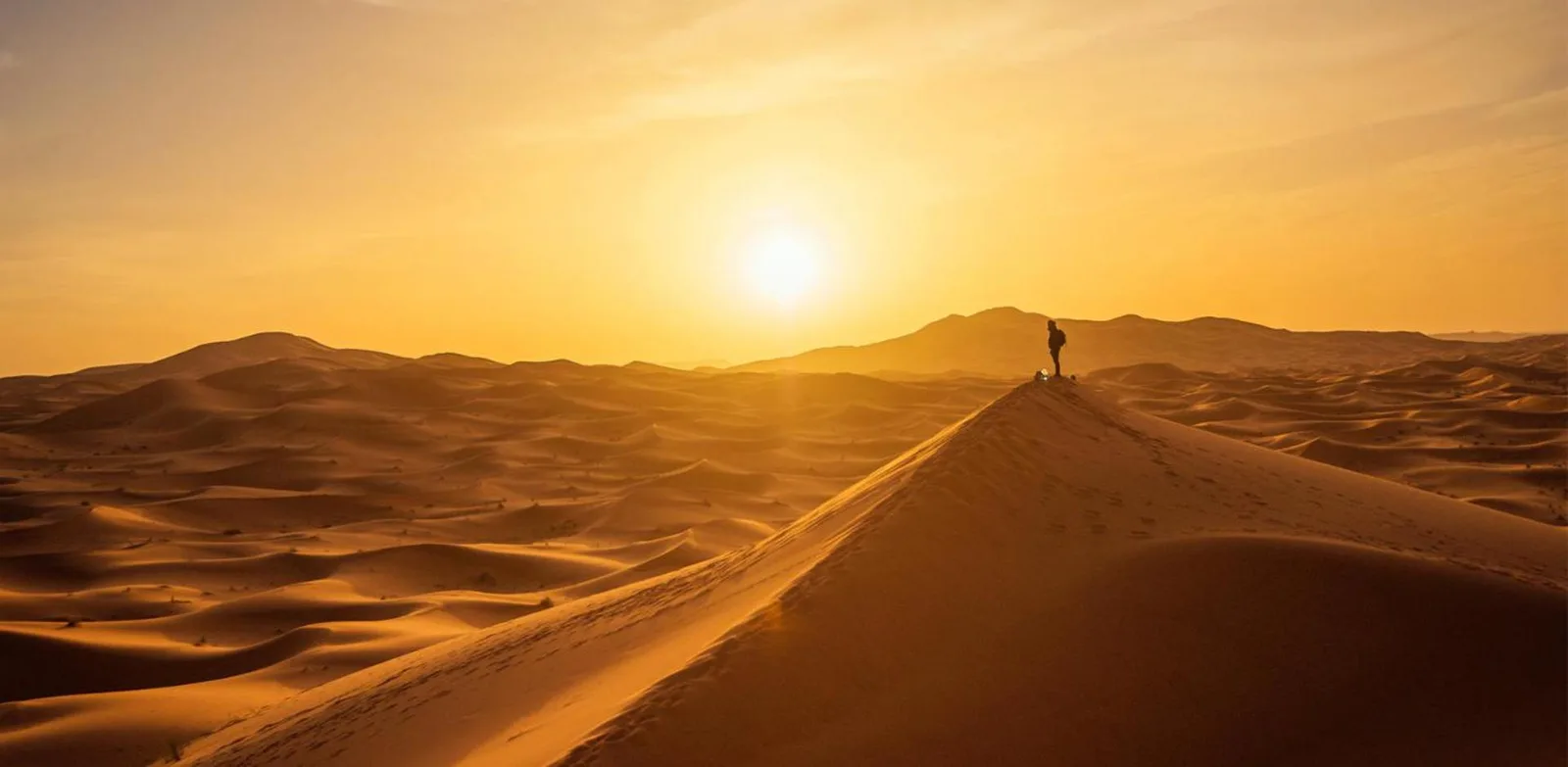 Sunset over the dunes near Erg Chebbi Luxury Camp in Merzouga with a lone figure on a ridge