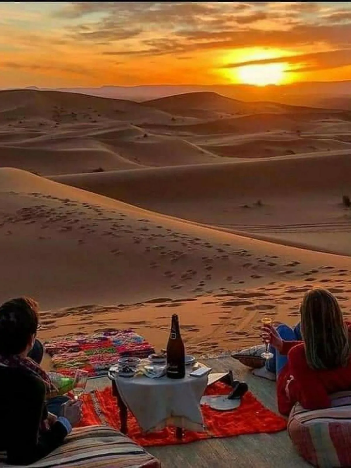 Guests enjoying a sunset picnic on the dunes near Erg Chebbi Luxury Camp in Merzouga