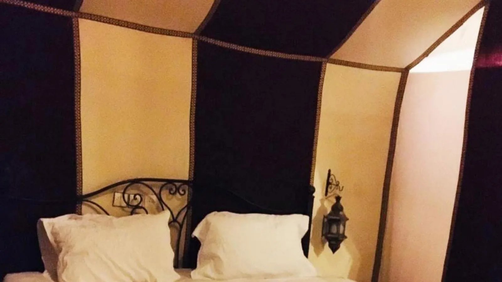 Tent bedroom interior at Erg Chebbi Luxury Camp in Merzouga with wrought iron bed frame and lantern