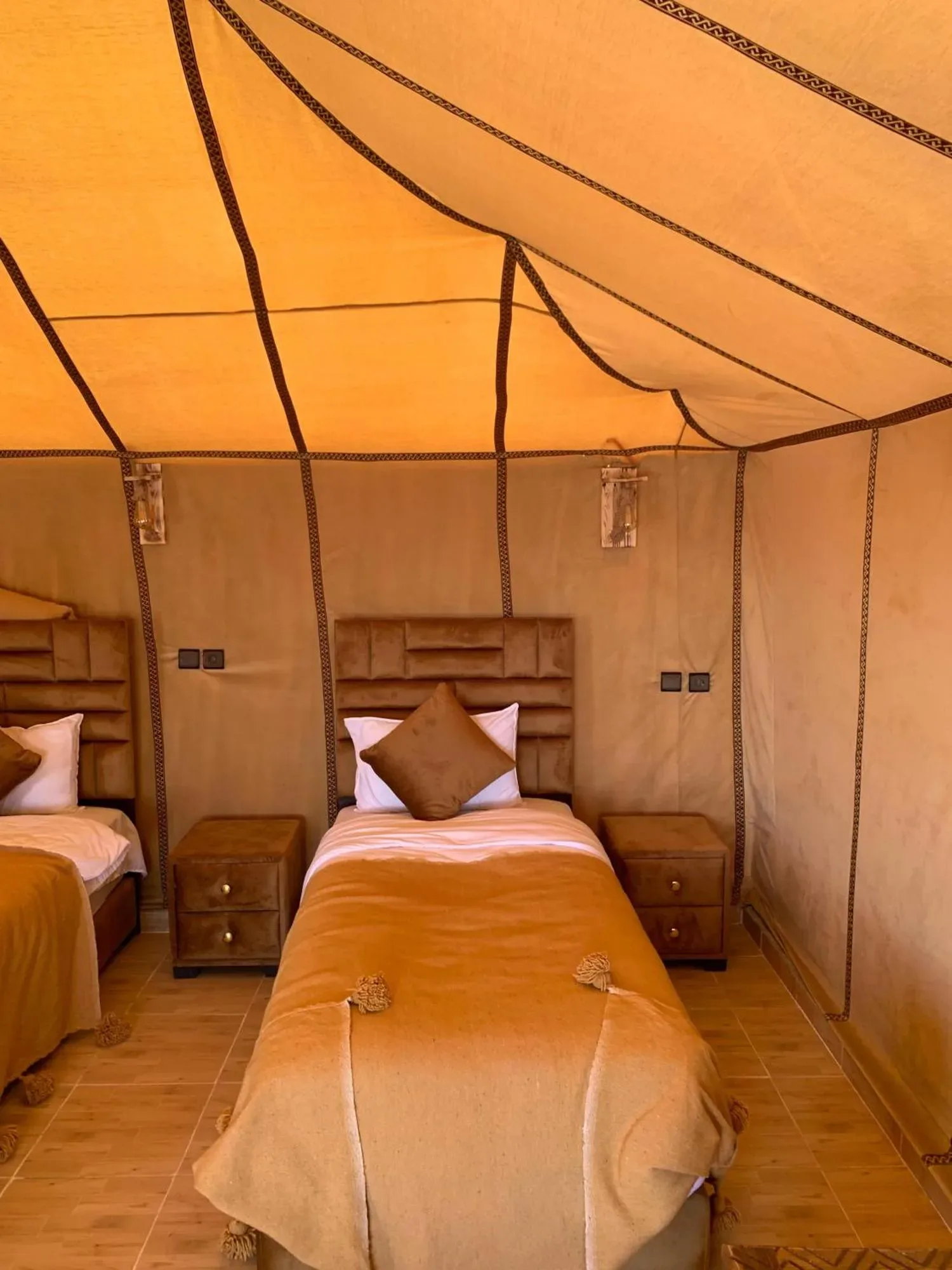 Habitación de tienda con dos camas en Erg Dream Luxury Camp en Merzouga, con decoración tradicional de campamento del desierto.
