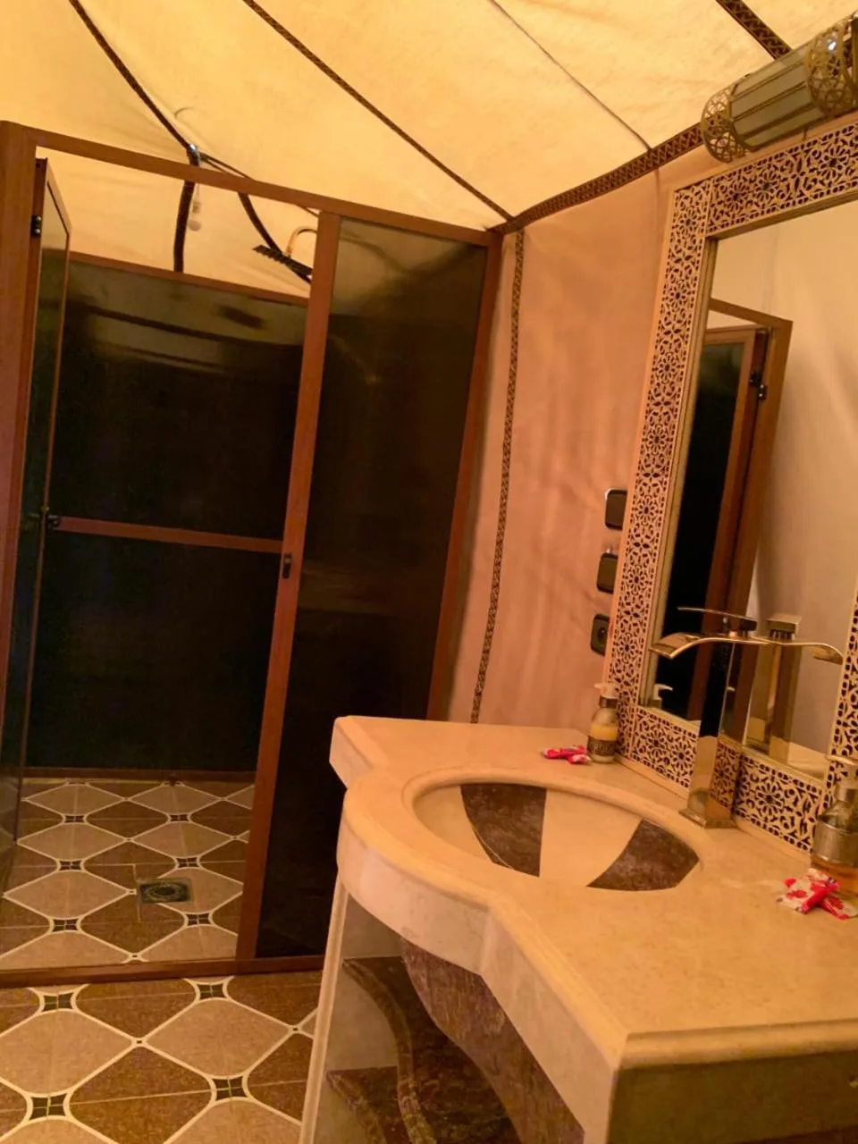 Mueble de baño en Erg Dream Luxury Camp en Merzouga, con espejo decorativo y lavabo.
