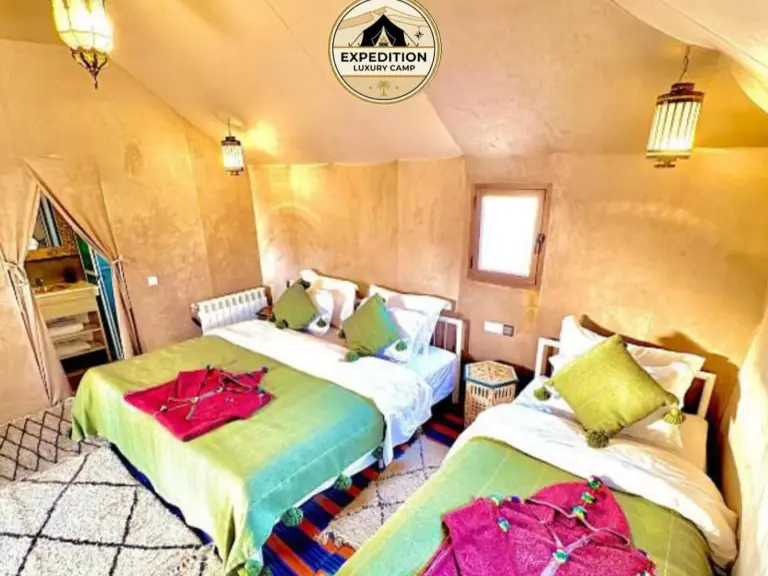 Tienda familiar de Expedition Luxury Camp en Merzouga con camas dobles, cojines de colores y estilo de campamento del desierto