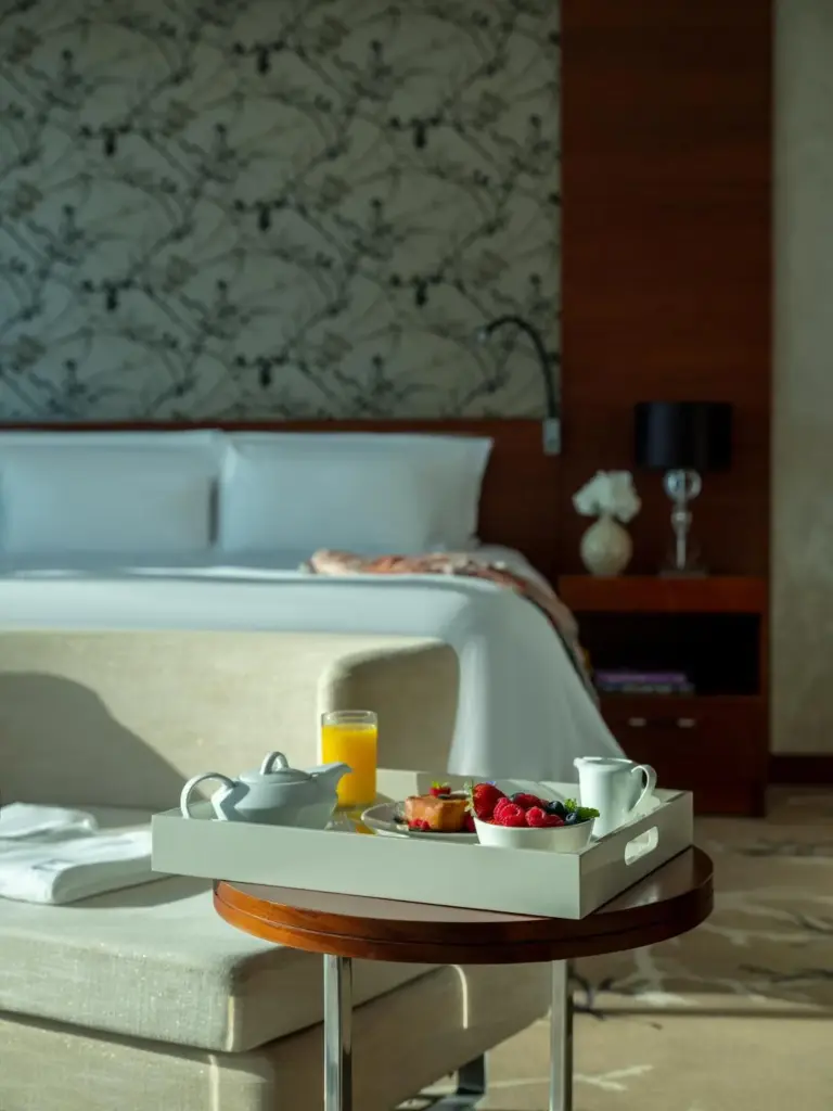 Fairmont Bab Al Bahr – hôtel à Abou Dabi, Émirats Arabes Unis – un plateau de nourriture sur une table à côté d'un lit au Fairmont Bab Al Bahr à Abou Dabi