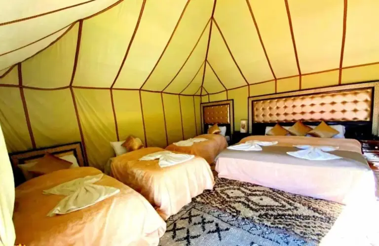Fantástico Campamento de Lujo – hotel en Merzouga, Marruecos – una habitación con tres camas en una tienda en Fantástico Campamento de Lujo en Merzouga