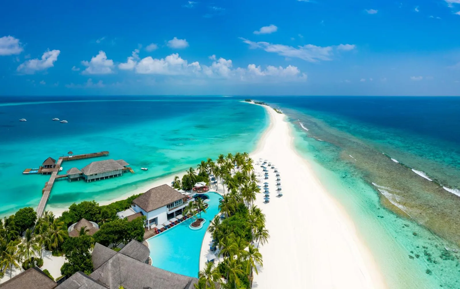 Aerial view of Finolhu, A Seaside Collection Resort showcasing its beautiful beach and lagoon.
