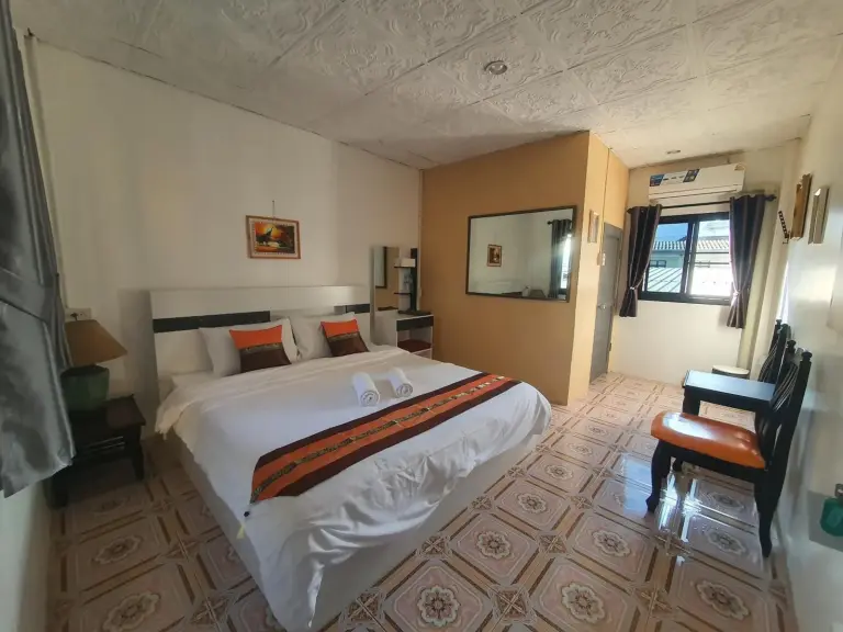 Dormitorio de Forge Boutique Chiang Mai con suelo estampado, cama, espejo y zona de estar