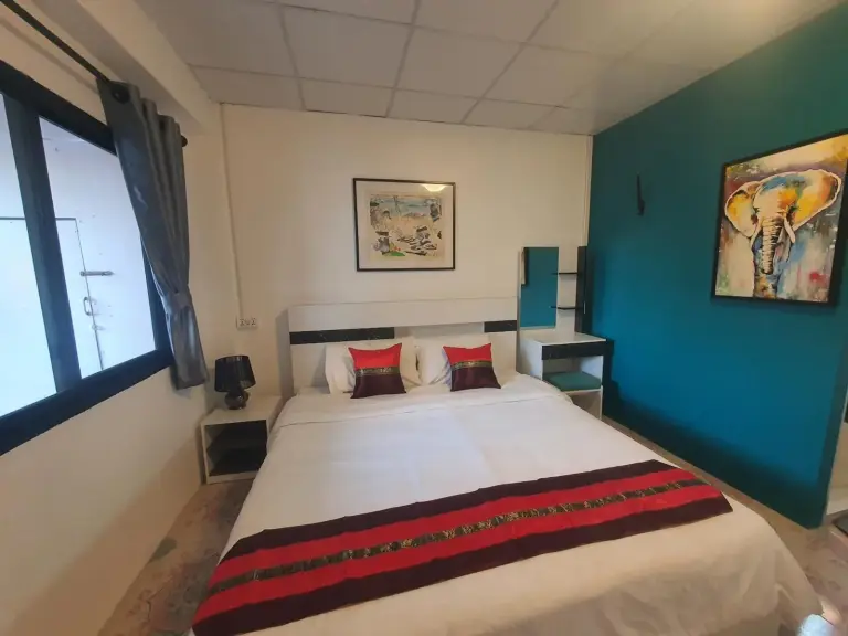 Habitación doble de Forge Boutique Chiang Mai con ropa de cama blanca y arte mural de elefantes