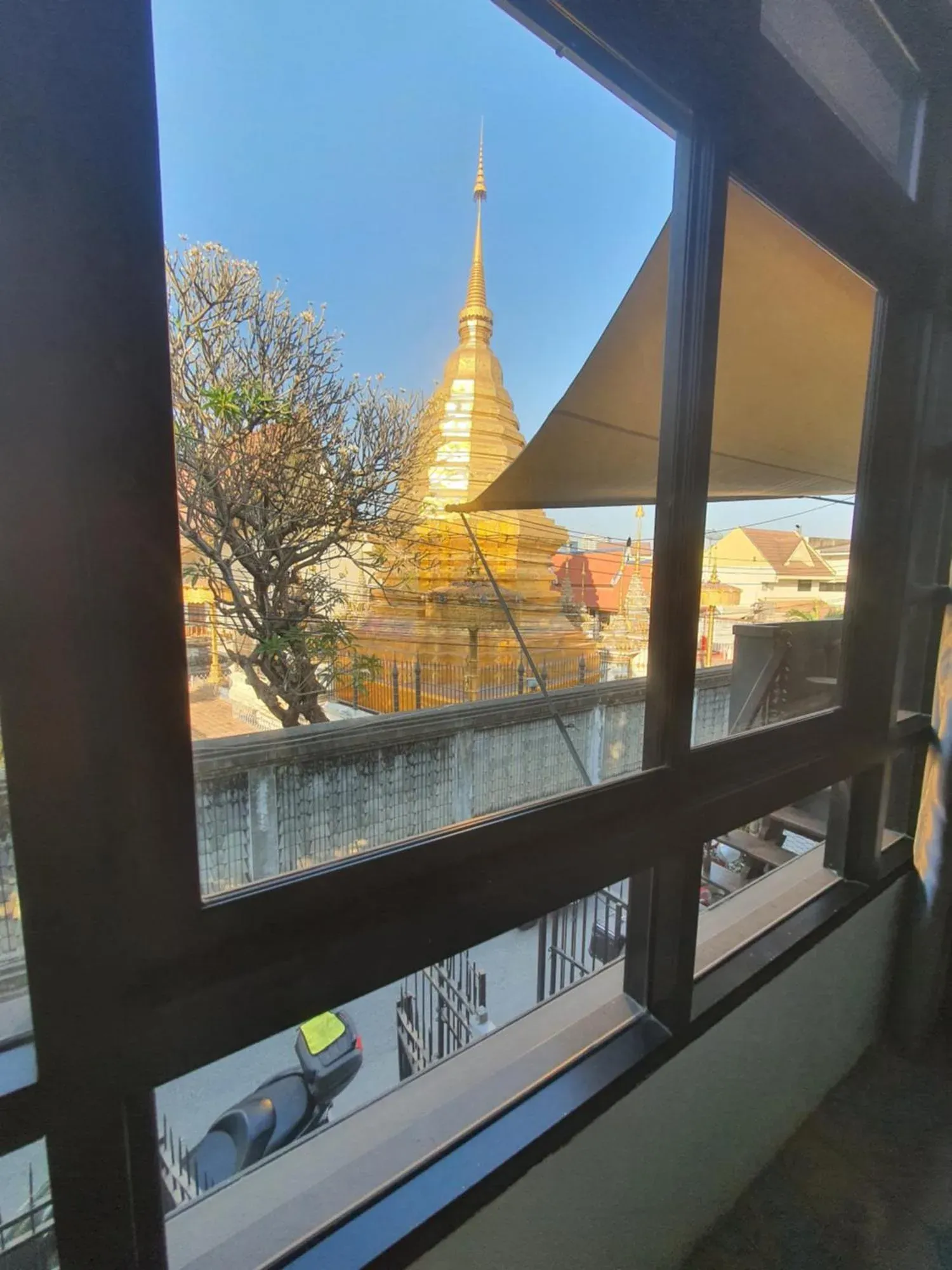Vista desde la ventana de una habitación de Forge Boutique Chiang Mai con una estupa de templo dorada y tejados de la ciudad
