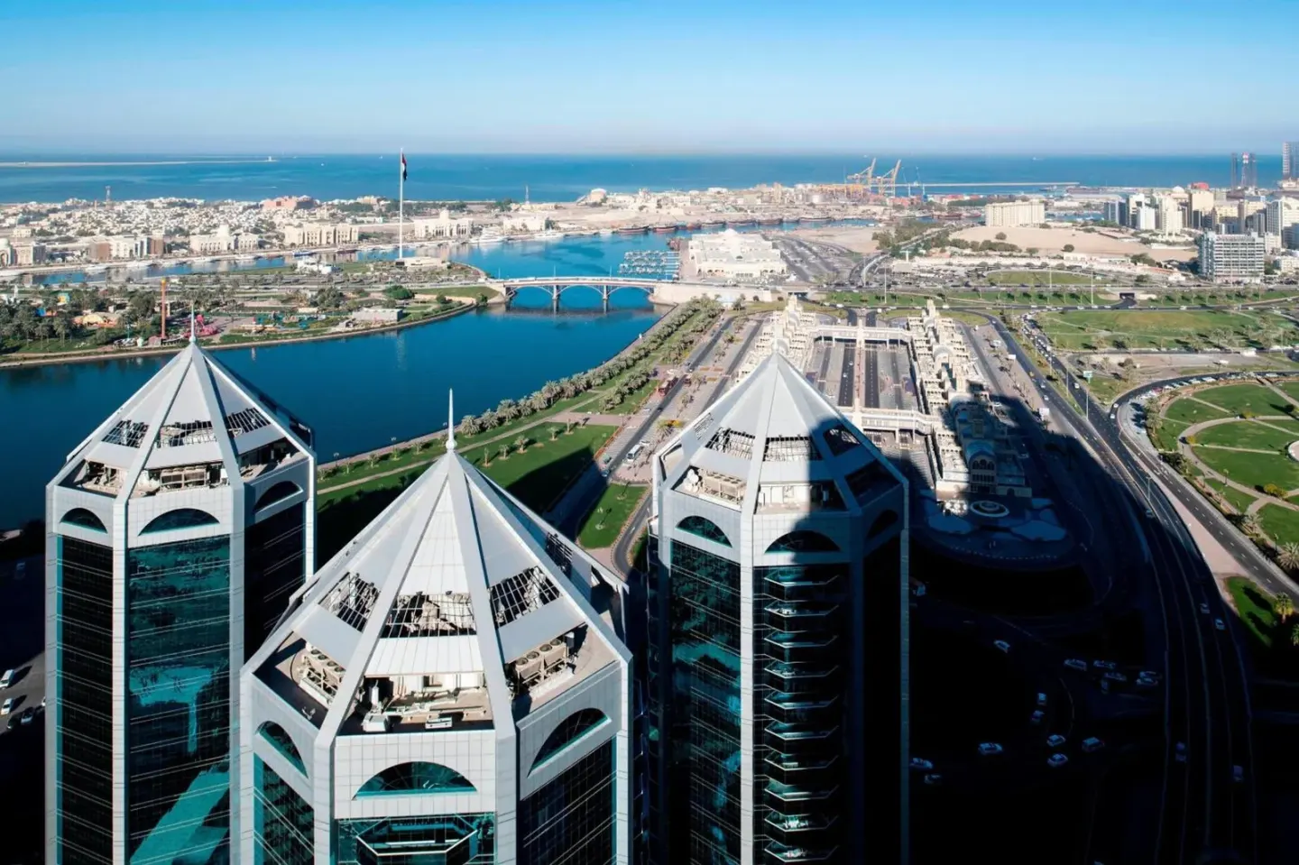 High-level aerial view from Four Points by Sheraton Sharjah overlooking the coast, roads, and city.