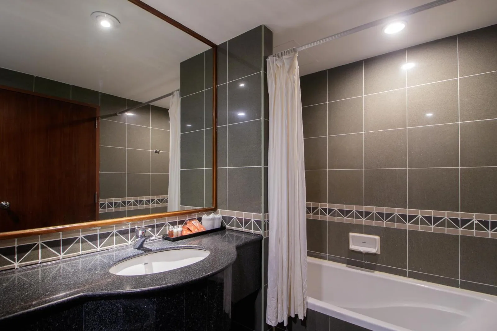 Salle de bains moderne à Garden Sea View Resort Pattaya avec baignoire, lavabo et grand miroir.